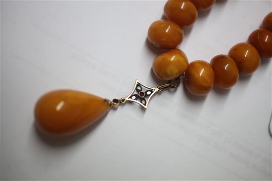 A single strand graduated disc shaped amber bead necklace with rose cut diamond and ruby set amber drop pendant, gross weight
